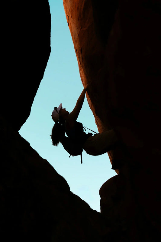Silhouette of a woman rock climbing outdoors